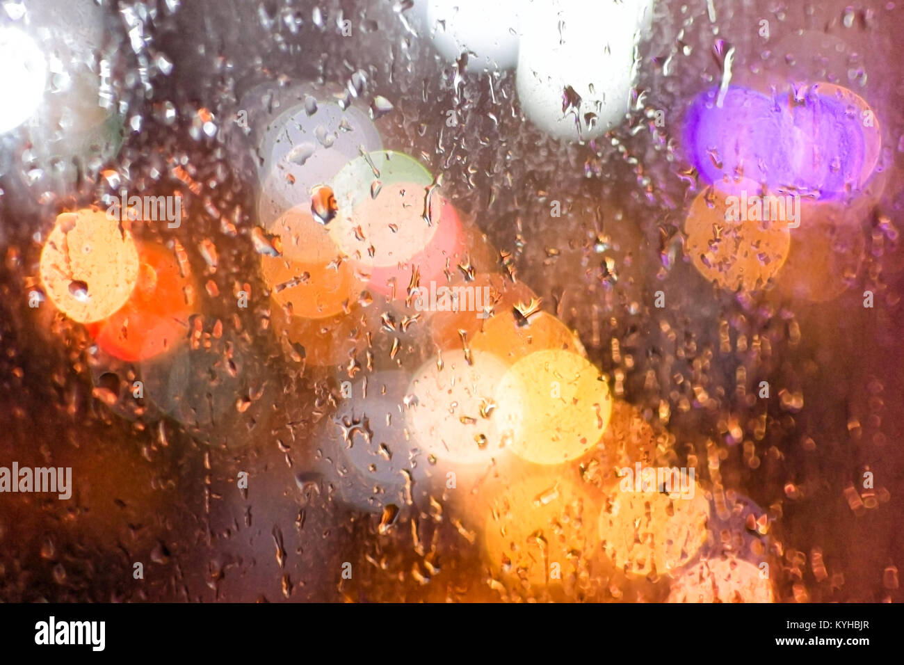 Gocce di pioggia su una finestra, sullo sfondo di un bokeh dalle luci della città, di notte. Foto Stock
