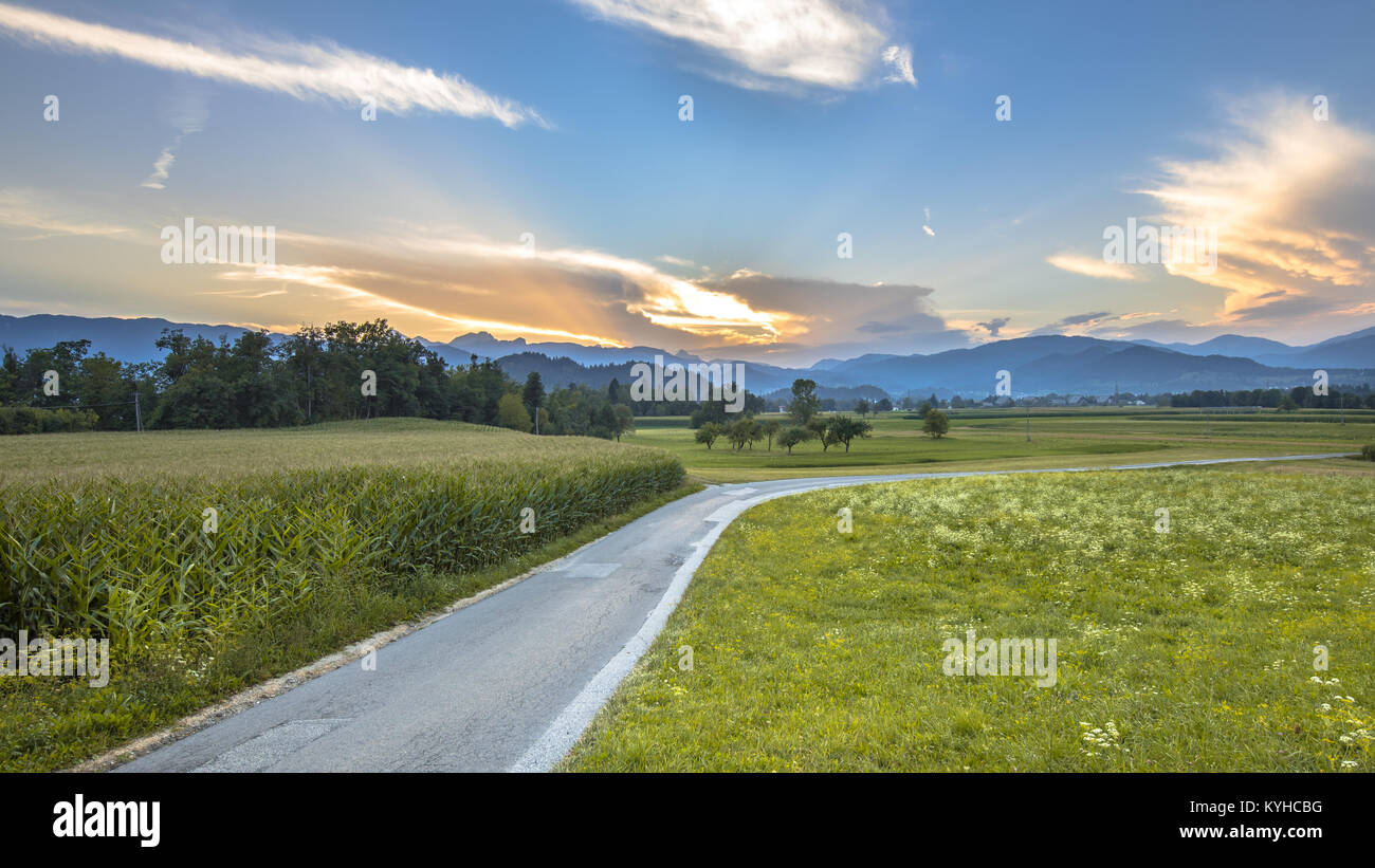 La strada attraverso la campagna slovena il paesaggio con le Alpi Giulie sullo sfondo vicino a Bled Foto Stock