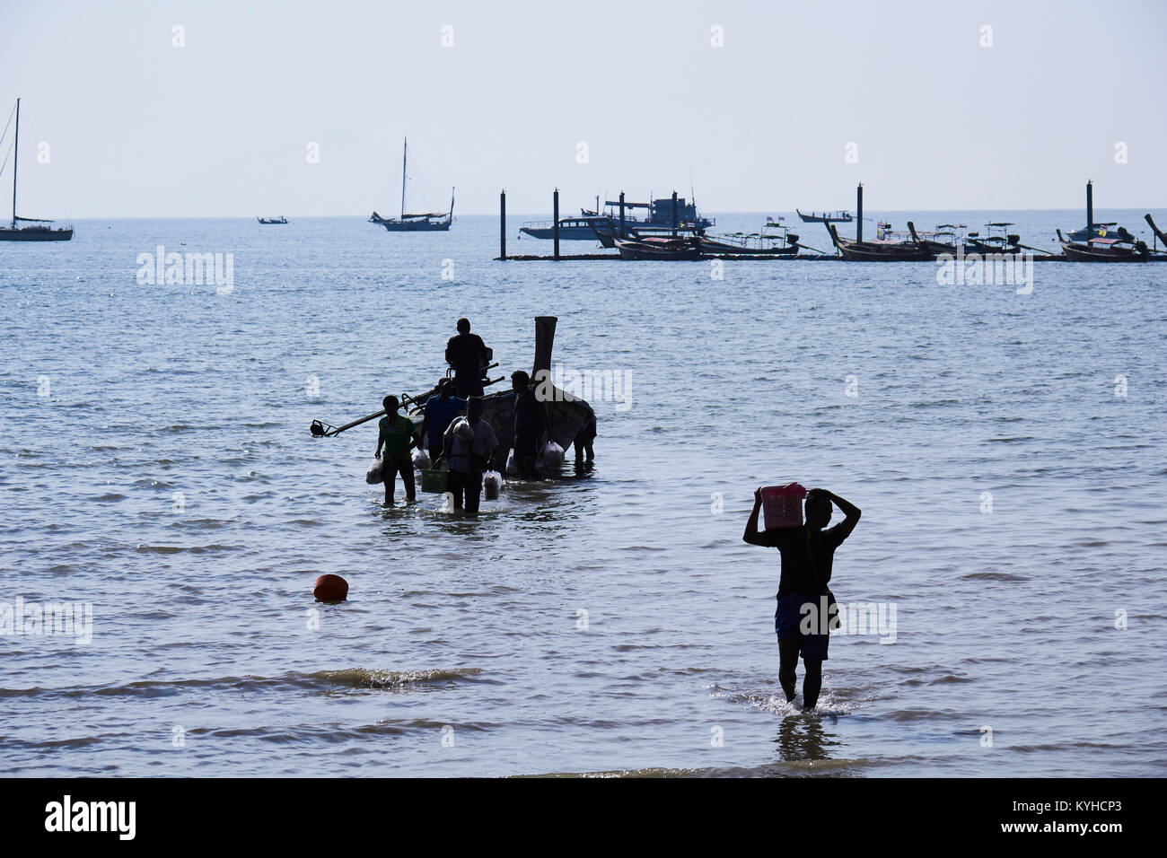 Il lavoro manuale. Lo scarico di merci da un tradizionale longtail boat a Railay Beach, Krabi Provence, Thailandia Foto Stock