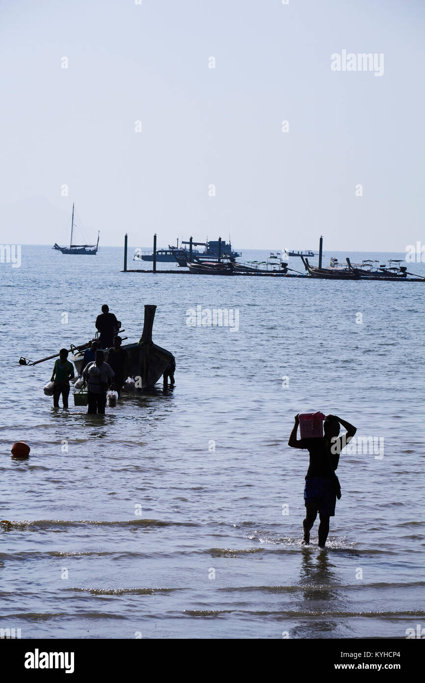 Il lavoro manuale. Lo scarico di merci da un tradizionale longtail boat a Railay Beach, Krabi Provence, Thailandia Foto Stock