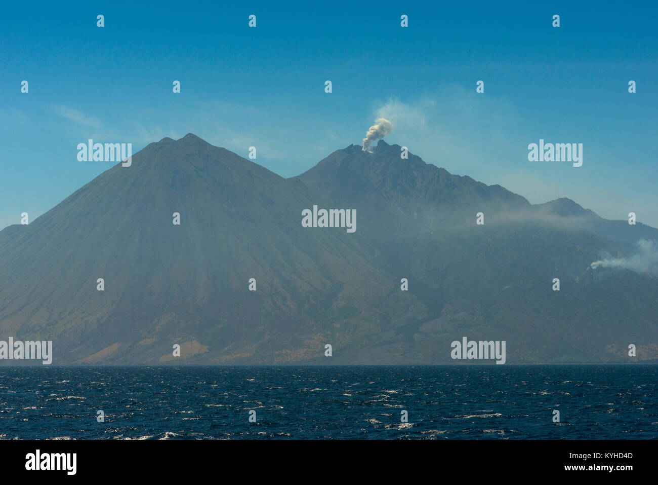 Una vista del vulcano di picchi e una piccola eruzione del vulcano attivo Api Sangeang (Gunung Api) off il nord-est di Sumbawa, Indonesia. Foto Stock