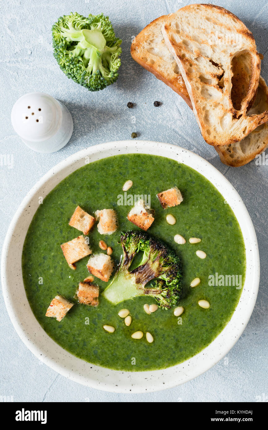 Crema di broccoli zuppa con crostini, olio di oliva e i pinoli in una terrina. Vista superiore, primo piano. Una sana alimentazione vegetariana Foto Stock