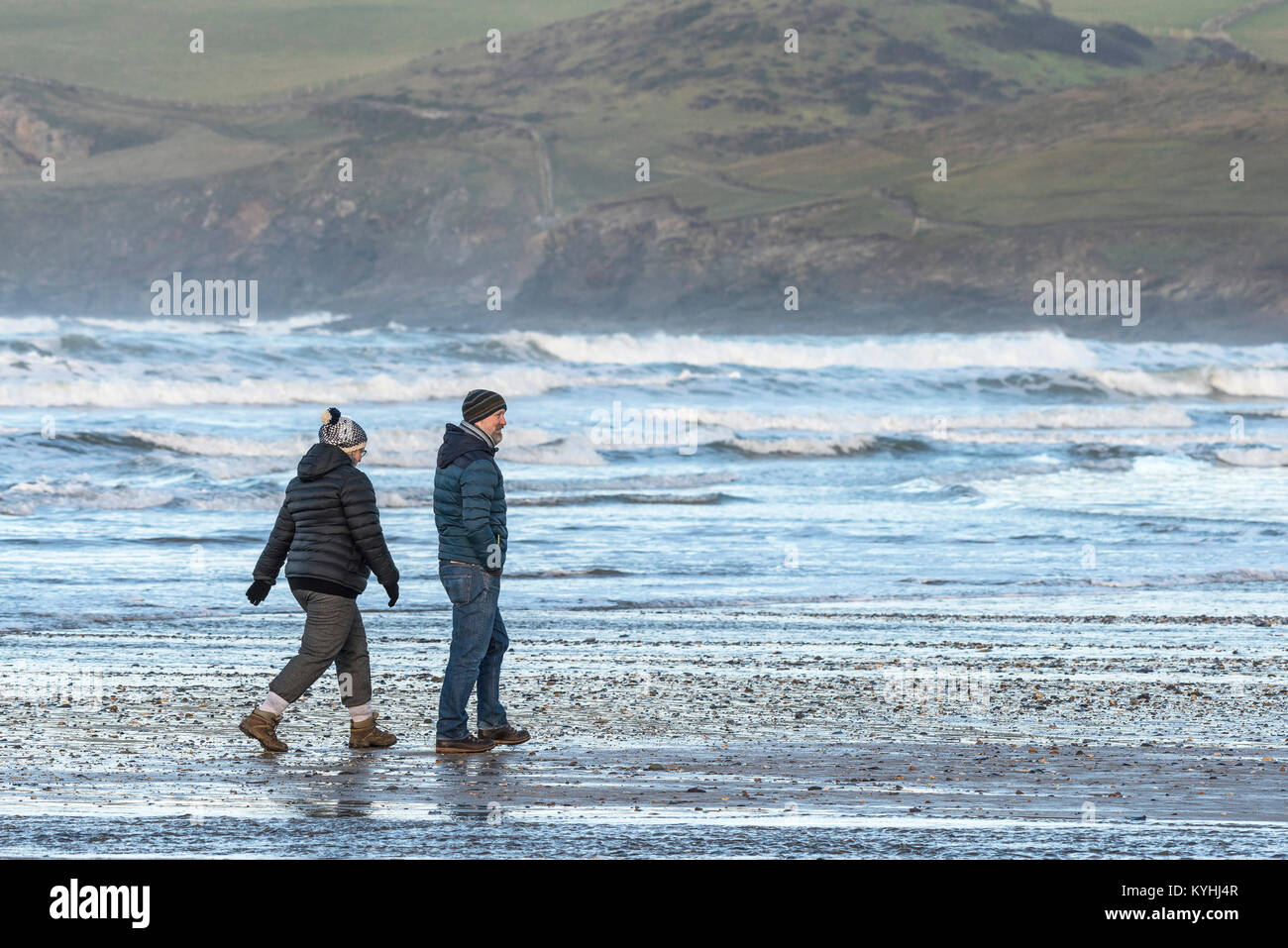 Polzeath - un paio di persone godendo di una passeggiata su Polzeath Beach a nord della costa della Cornovaglia. Foto Stock