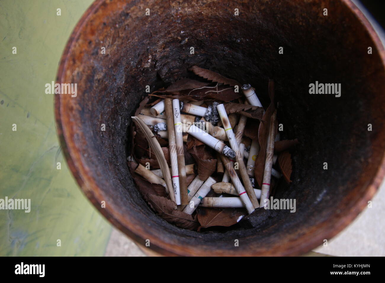 Mozziconi di sigaretta e foglie marrone all'interno di rusty portacenere Foto Stock