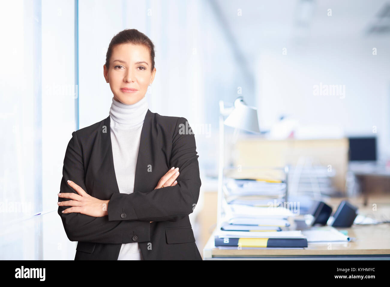 Un sorridente executive advisor finanziario imprenditrice in piedi con le braccia incrociate all'ufficio. Foto Stock