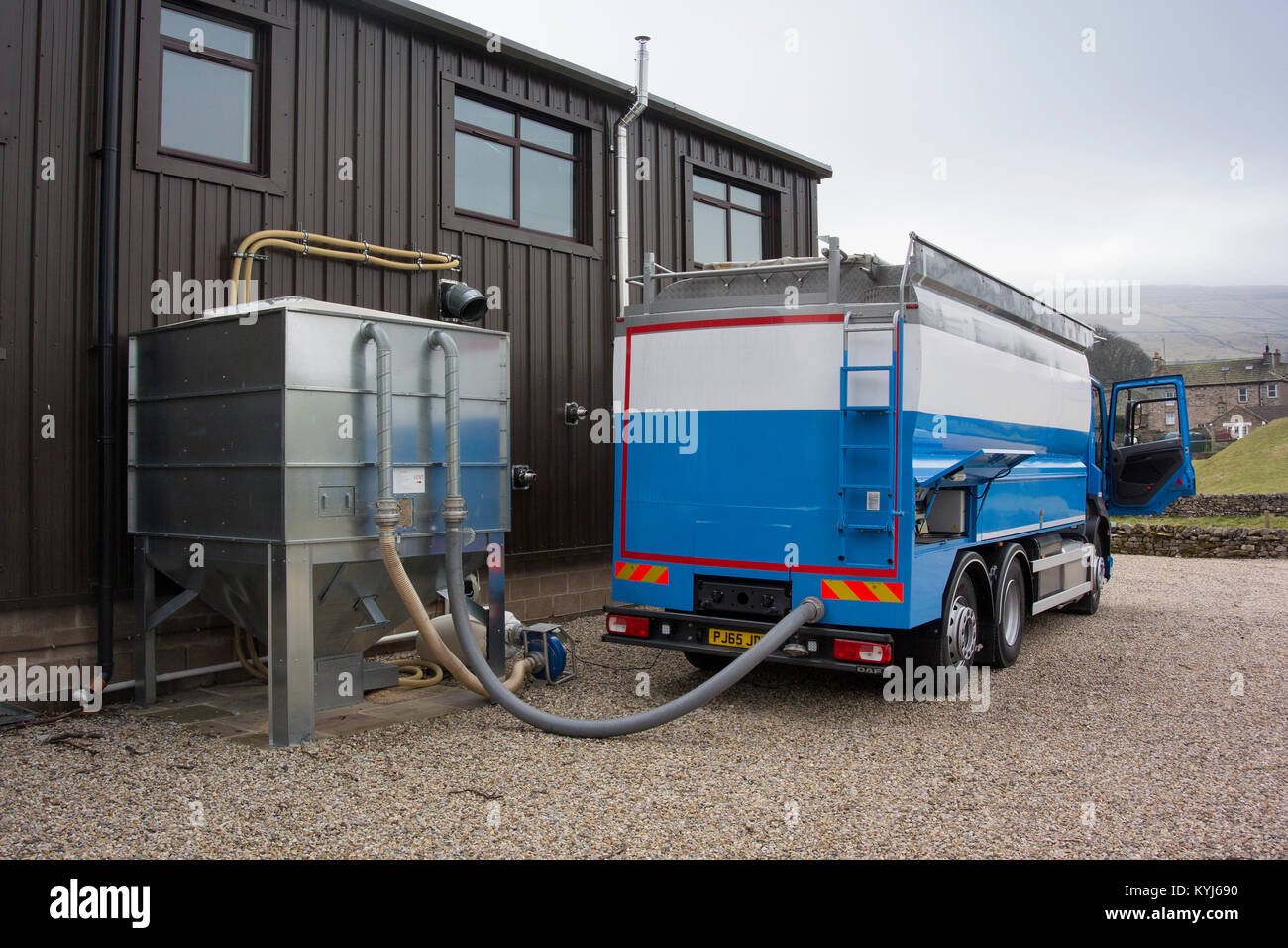 Pellet di legno che viene erogata in una tramoggia di sfusi per uso in Bio riscaldatore del carburante in un parco industriale, UK. Foto Stock