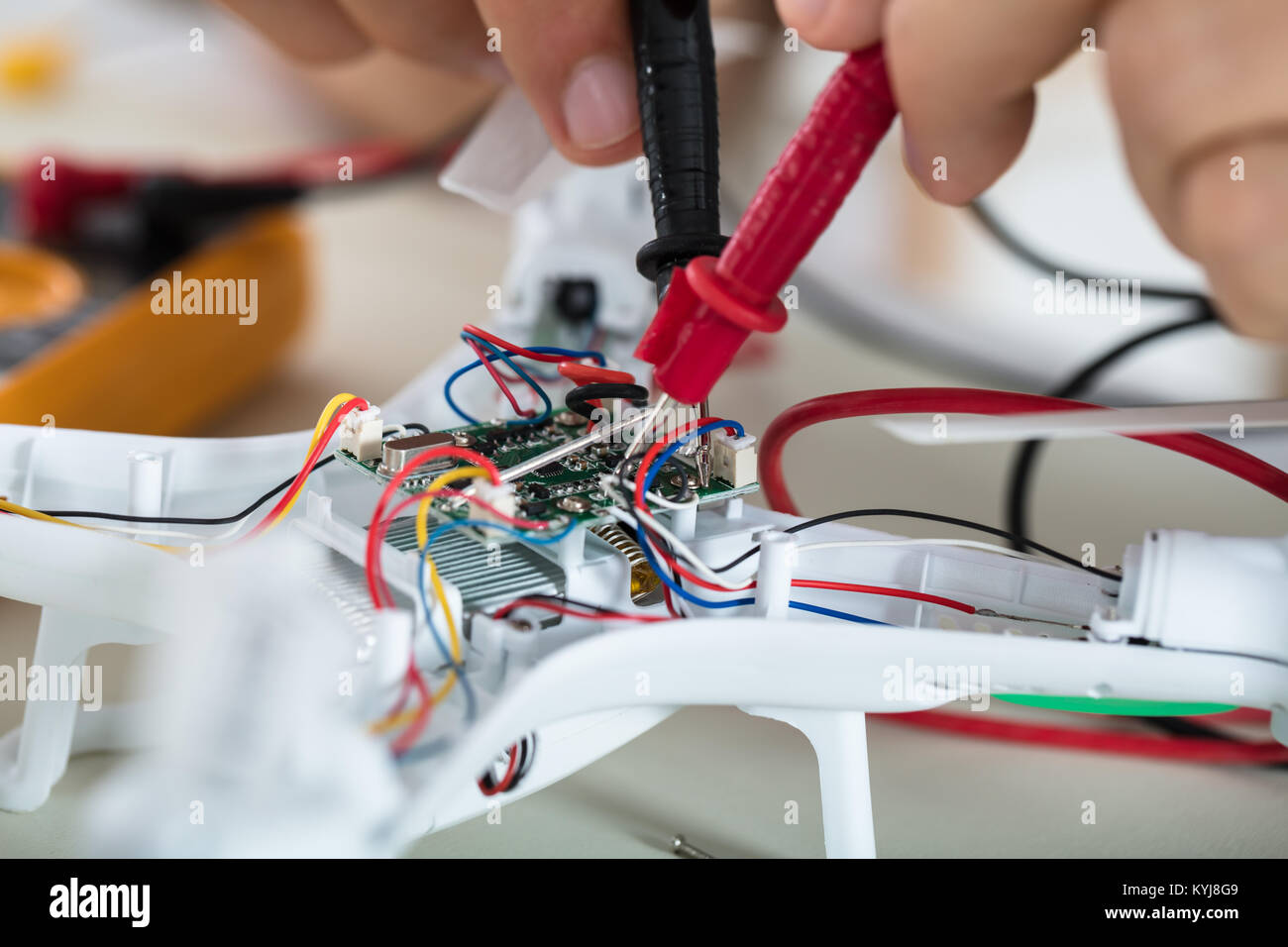 Close-up di un uomo prova corrente elettrica del Drone smontato utilizzando lo strumento del multimetro Foto Stock