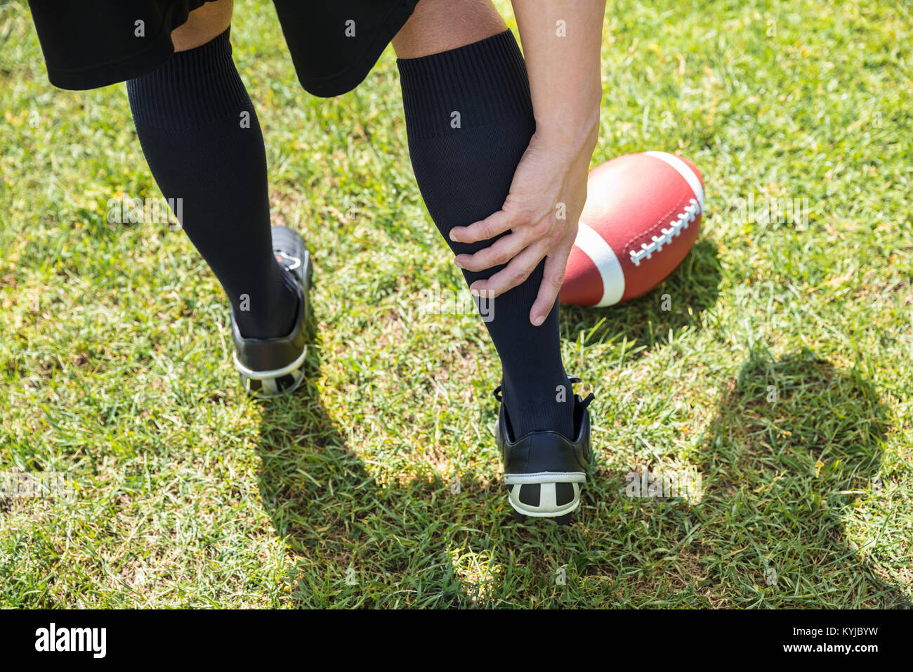 Vista in elevazione del giocatore di football americano con il dolore nella sua parte inferiore della gamba sul campo Foto Stock