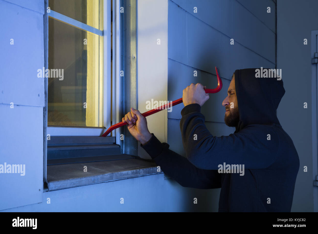 Close-up di rapinatore nel cofano usando il piede di porco Rosso Per aprire la finestra in vetro Foto Stock