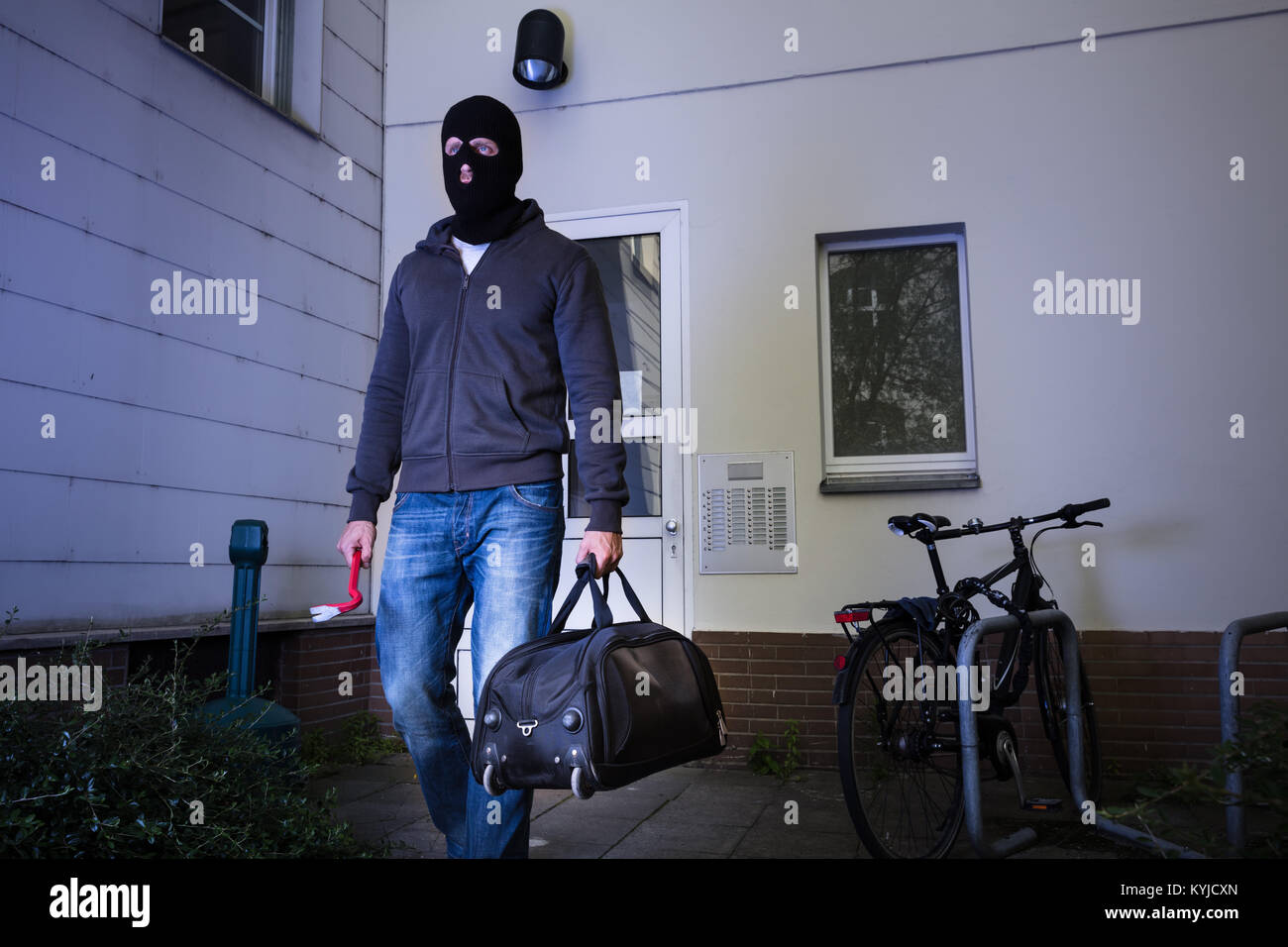 Ladro in maschera nera fuggire con borsetta dopo aver rubato da casa Foto Stock