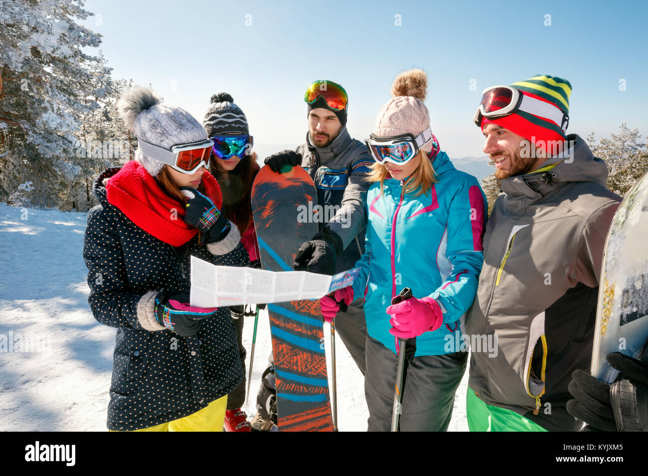 Gruppo di amici la lettura di una mappa su carta in inverno vacanze in montagna innevata Foto Stock