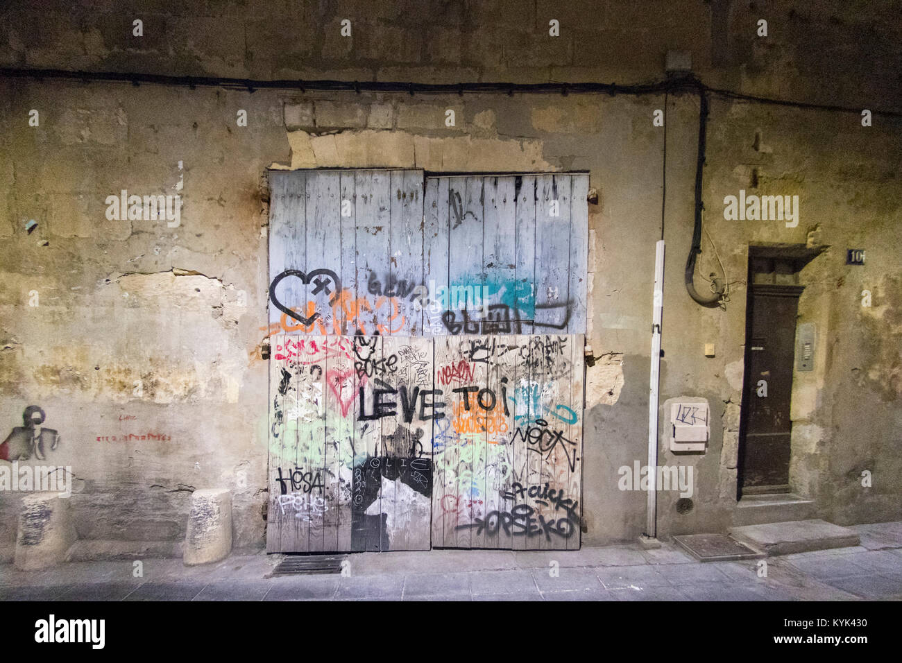 Grafitti sul vecchio portale in legno di notte nella parte vecchia di Arles, Francia Foto Stock