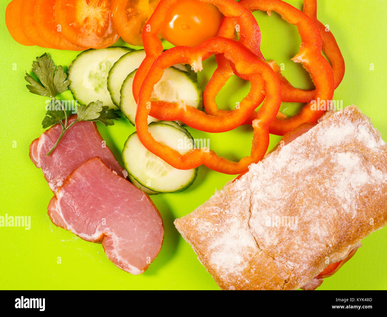 Tema alimentare ancora in vita. Carne, pane e verdure su sfondo verde. Vista superiore Foto Stock