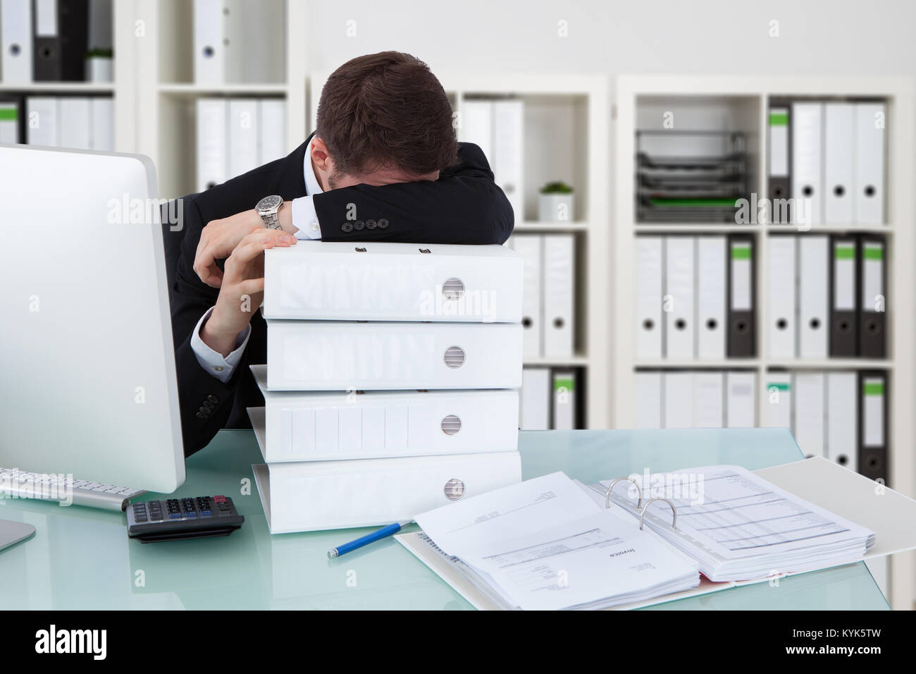 Imprenditore di dormire sulla pila di cartelle in ufficio Foto Stock