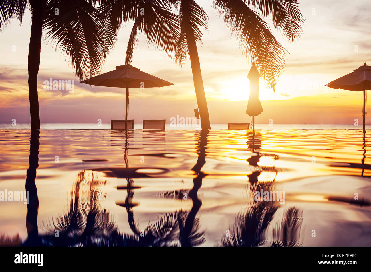 Spiaggia piscina al tramonto con la riflessione di palme, paesaggio tropicale, esotici island hotel Foto Stock