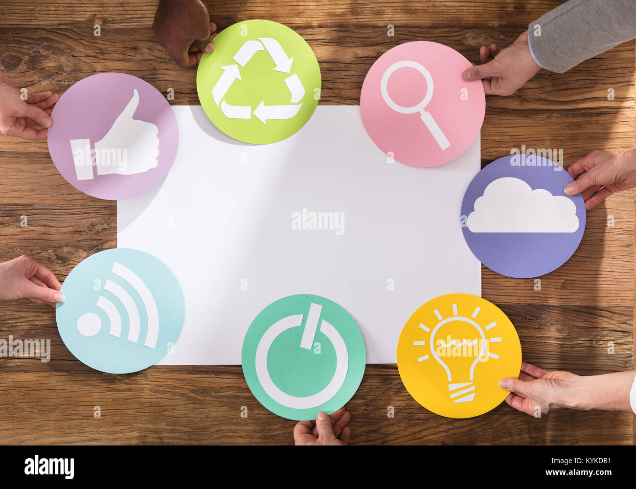 Gruppo di imprenditori tenendo i vari simboli aziendali sul tavolo di legno Foto Stock