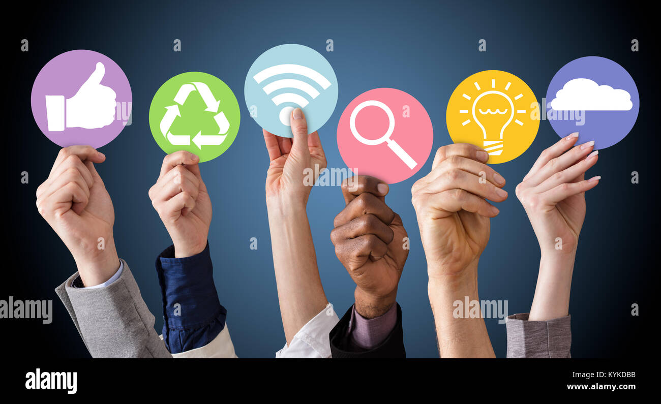 Gli imprenditori mani tenendo vari simboli aziendali contro lo sfondo blu Foto Stock