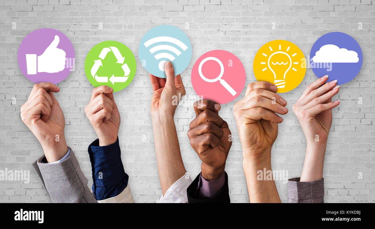 Gli imprenditori mani tenendo vari simboli aziendali contro il bianco muro di mattoni Foto Stock