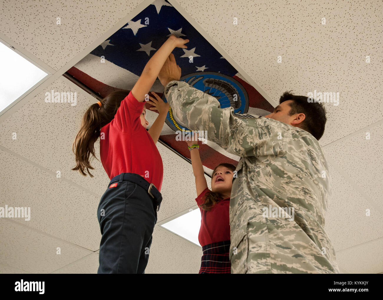 Master Sgt. Joey Youdell, un pararescueman nel 123Tattiche speciali Squadron, installa un custom-soffitto dipinto in piastrella il morale, del benessere degli animali e della struttura ricreativa al Kentucky Air National Guard Base in Louisville, KY., nov. 21, 2013. La struttura dispone di piastrelle per soffitto raffiguranti le missioni delle varie unità sulla base. Youdell dipinse la piastrella con l aiuto delle sue figlie, Giulietta e Olivia. (U.S. Air National Guard foto di magg. Dale Greer) Foto Stock