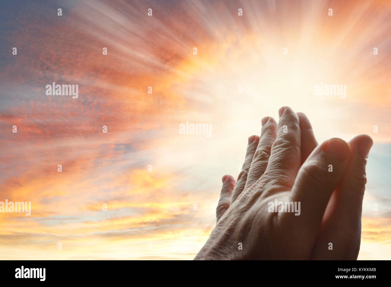 Le mani insieme a pregare in cielo luminoso Foto Stock
