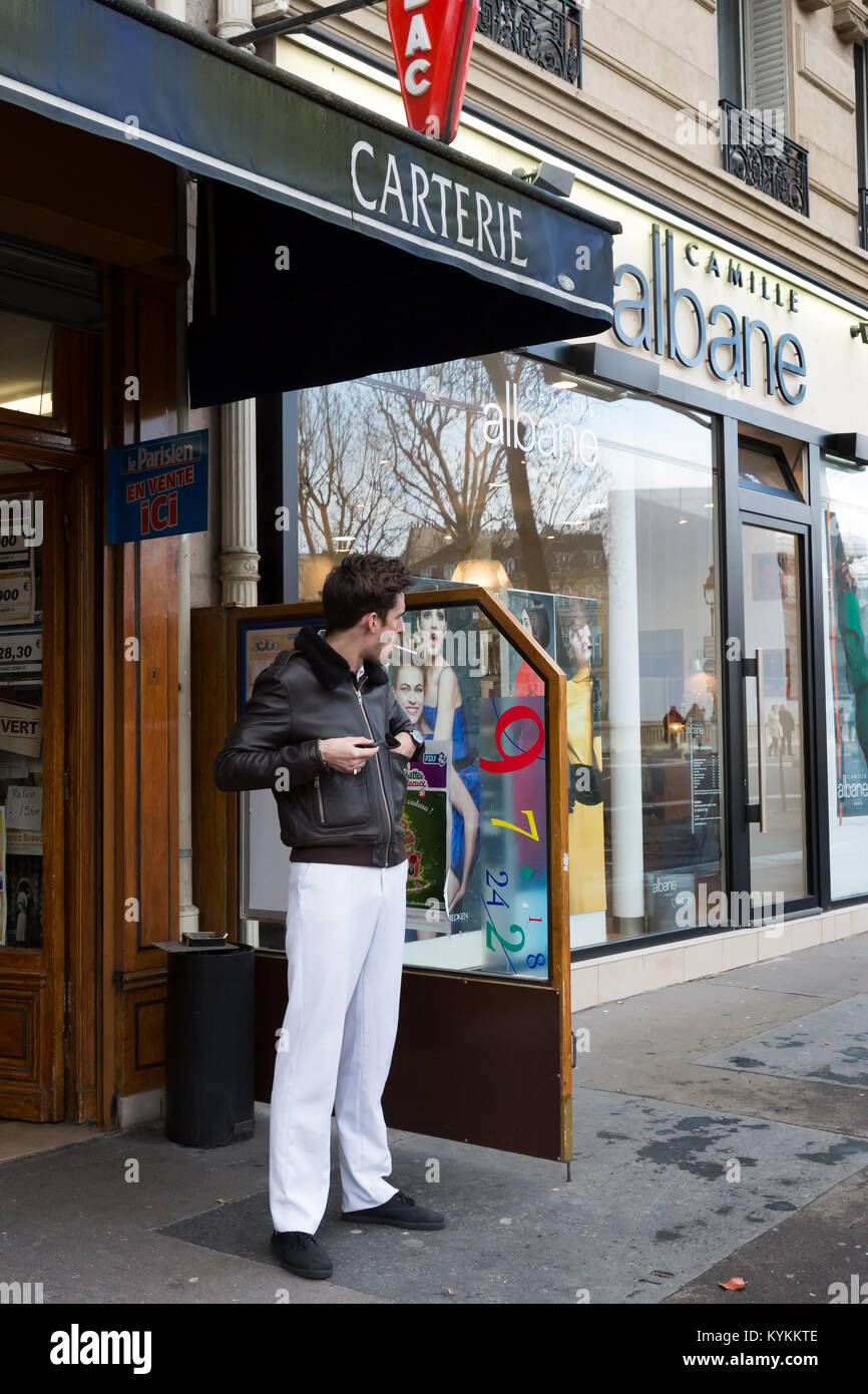 Parigi-GEN 4, 2014: un uomo fuma una sigaretta mentre in piedi al di fuori di una tabac shop, un negozio con licenza per la vendita di prodotti del tabacco. I tabacchini e sono identificati da un Foto Stock