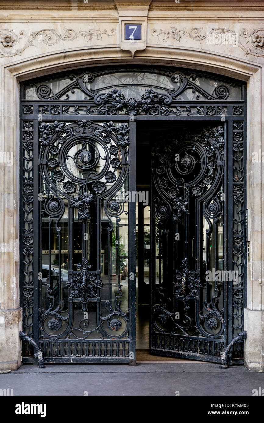 Parigi art nouveau in ferro e vetro porte doppie in un raffinato design. Una porta è parzialmente aperta dalla strada. Il numero di riferimento 7. Foto Stock