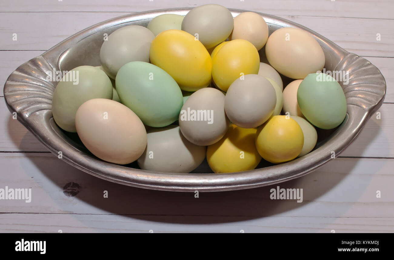 Un vassoio di argento pieno di uova di Pasqua di diversi colori recante su di un tavolo di legno Foto Stock