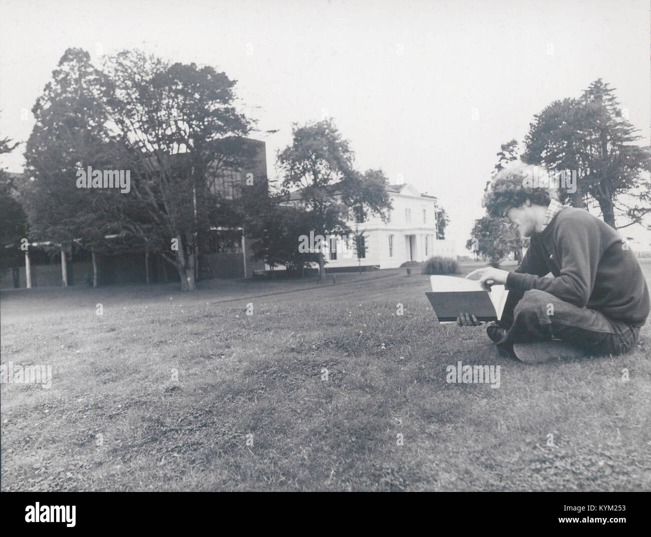 Una fotografia che mostra uno studente in piedi sul prato di fronte a Plassey House. L'immagine cattura un momento della vita del campus in una storica istituzione educativa. Foto Stock