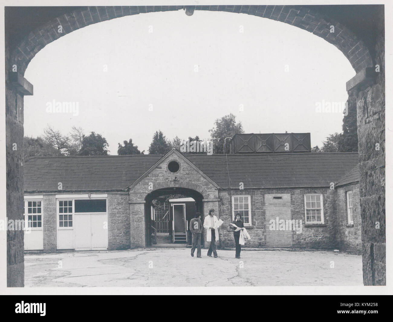 Questa fotografia della fine degli anni '1970 mostra tre studenti nel cortile di una stalla, che riflette le attività accademiche o agricole del periodo. Foto Stock