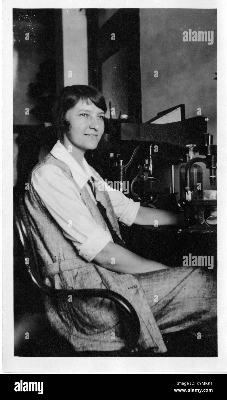 Un ritratto storico di Marie Agnes Hinrichs, una donna pionieristica nel campo della zoologia e dell'embriologia, scattato all'inizio del XX secolo. Hinrichs viene mostrata seduta alla sua scrivania, usando un microscopio per condurre ricerche sulle radiazioni e sulla luce ultravioletta. Foto Stock