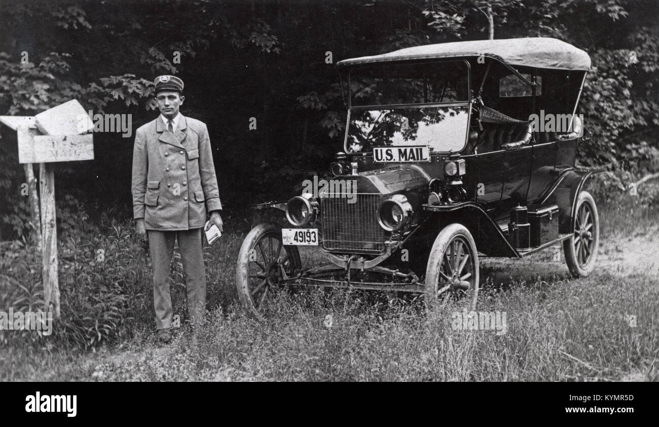 Una fotografia di un corriere di lettere rurale in uniforme, in piedi accanto a un veicolo Model T utilizzato per la consegna della posta nel 1914, che mostra l'evoluzione dei servizi di consegna della posta all'inizio del XX secolo. Foto Stock