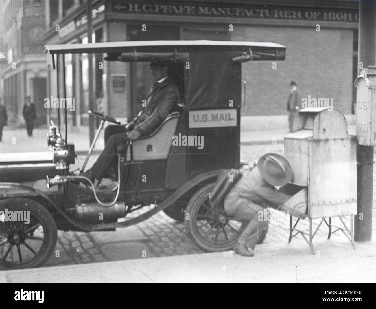 Questa fotografia storica mostra un corriere postale che consegna lettere in una Touring Car Columbia Mark 3, evidenziando i metodi di consegna postale degli inizi del XX secolo negli Stati Uniti Foto Stock