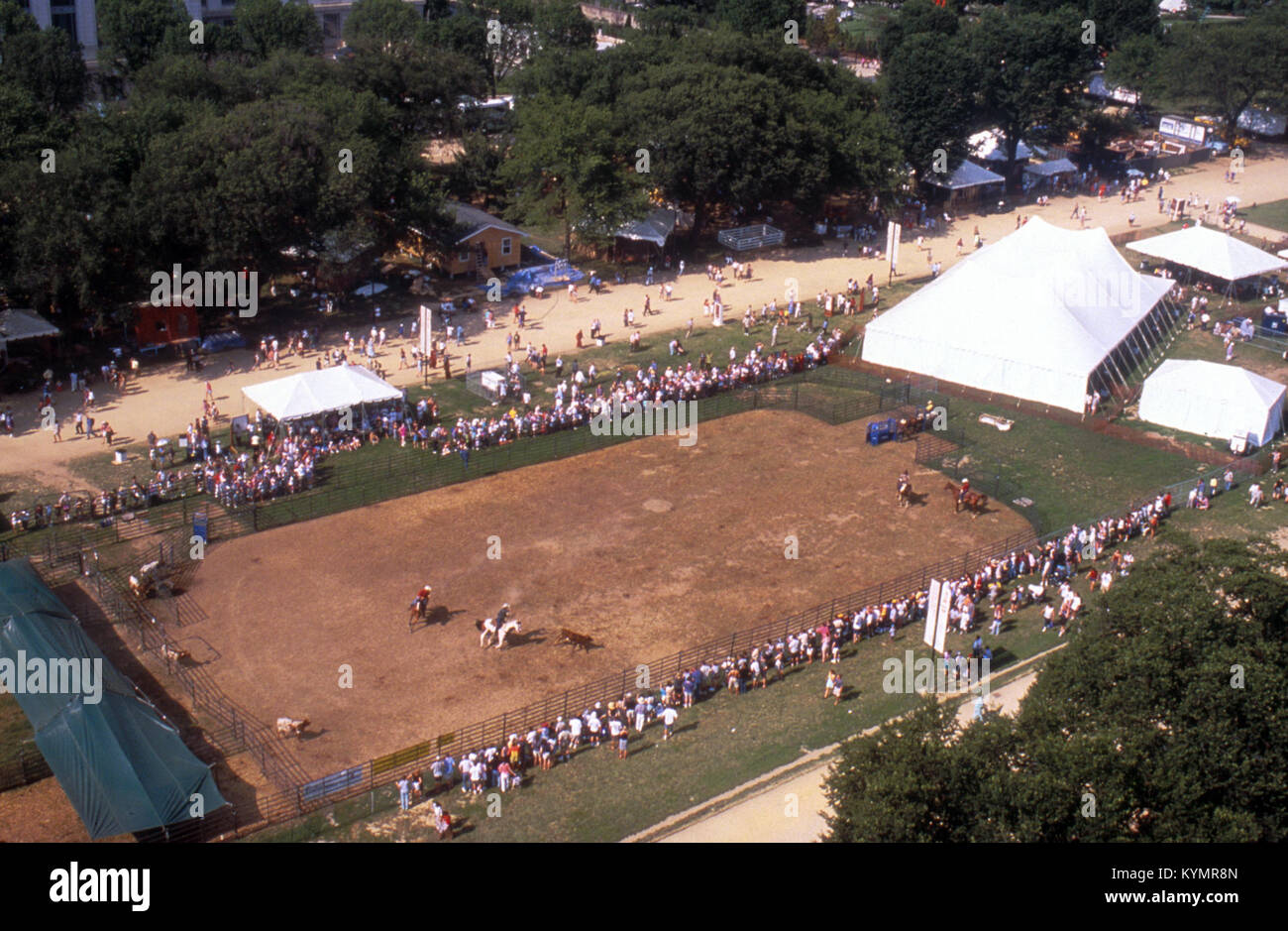 Una fotografia scattata per il Centro per il Folklife e i beni culturali, raffigurante una folla in un evento. Questa immagine storica cattura un festival folklife, con persone che si impegnano in attività culturali come il roping del bestiame e le dimostrazioni di cavalli. Foto Stock