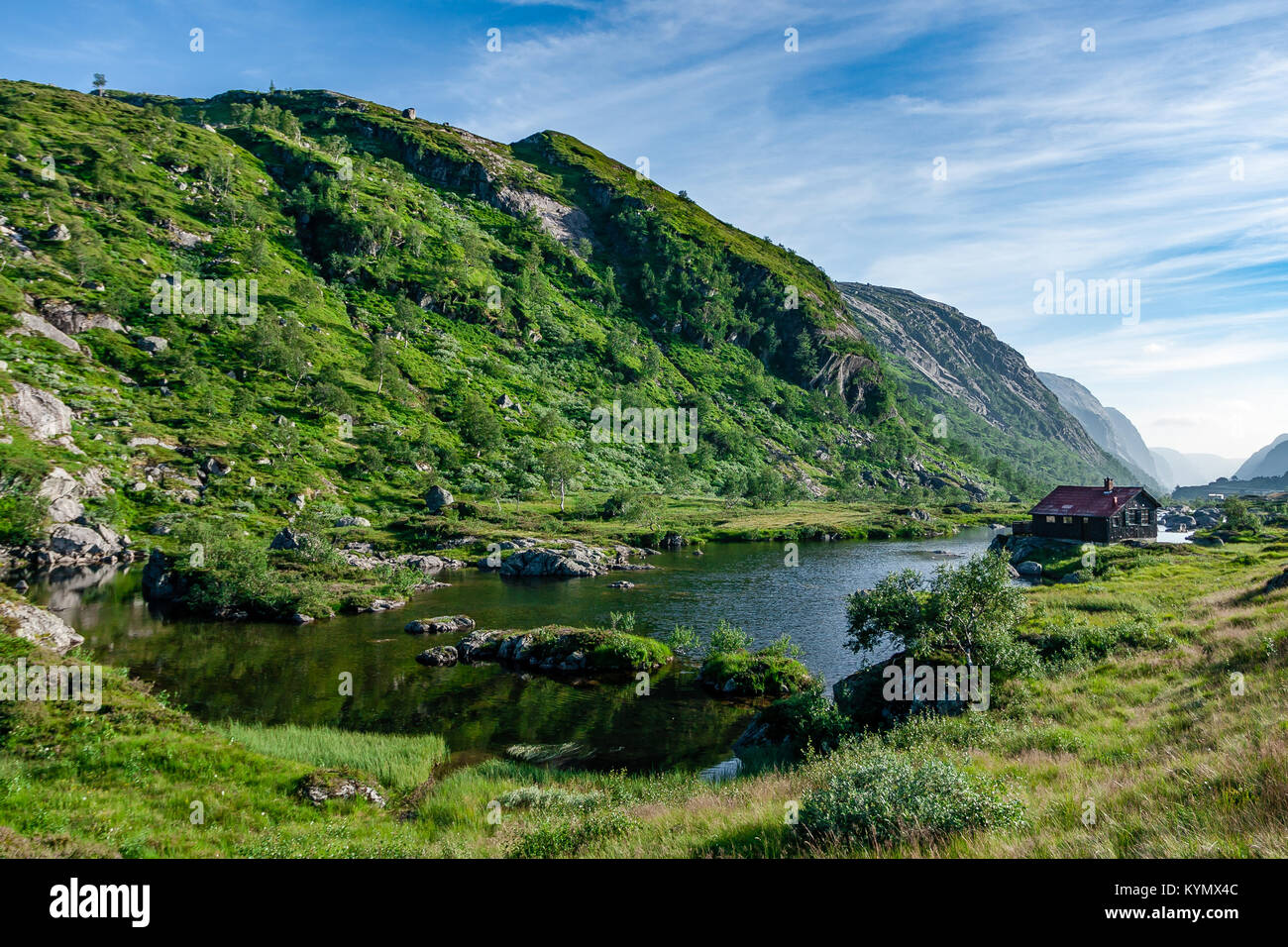 Bellissima valle norvegese in una limpida giornata estiva con la tradizionale casa in legno in background seduti al fiordo banca. Foto Stock