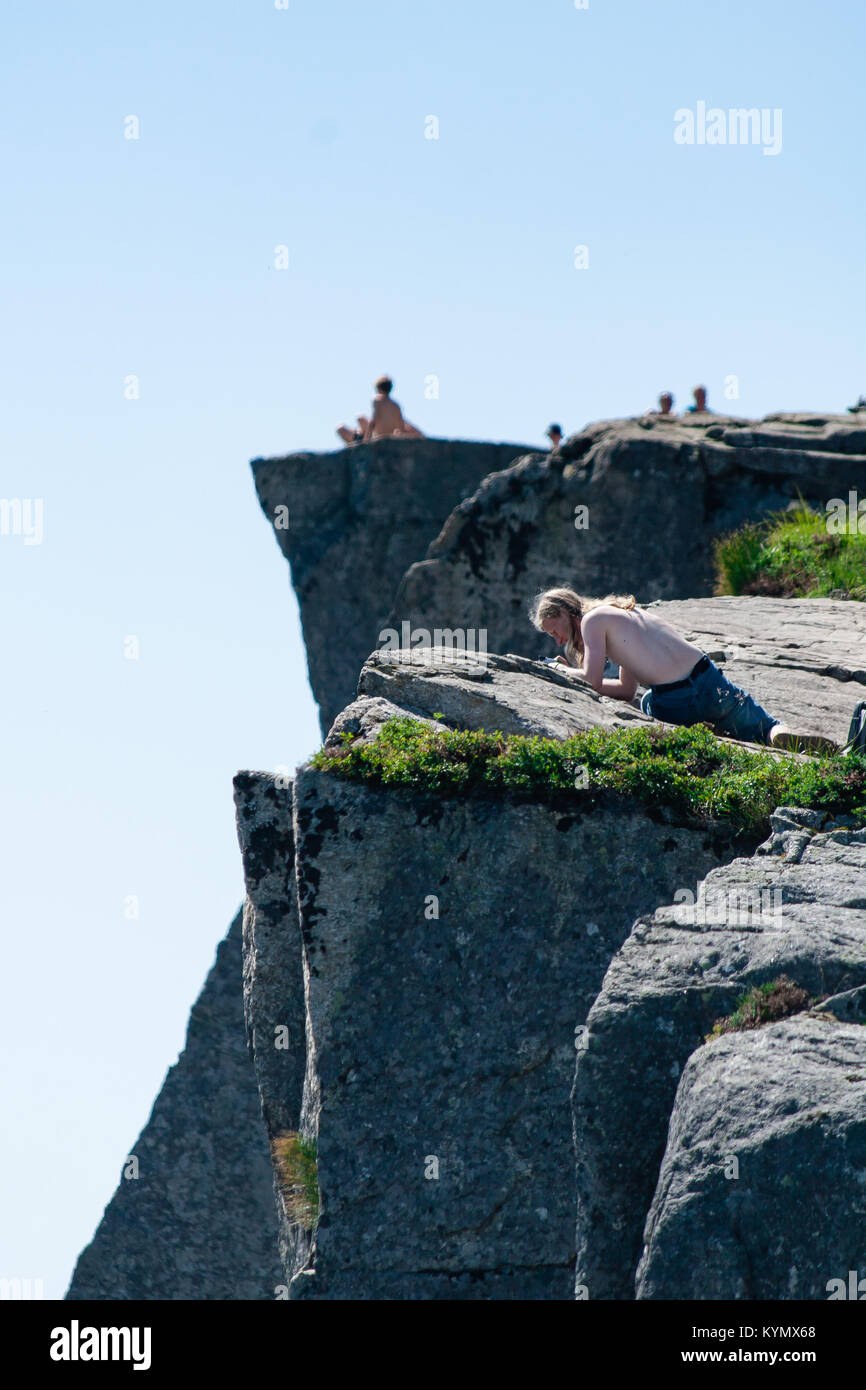 Uomo che guarda in basso la ripida scogliera sul pulpito Rock Prekestolen - una scogliera che sorge a 604 metri sopra il Lysefjorden in Norvegia Foto Stock