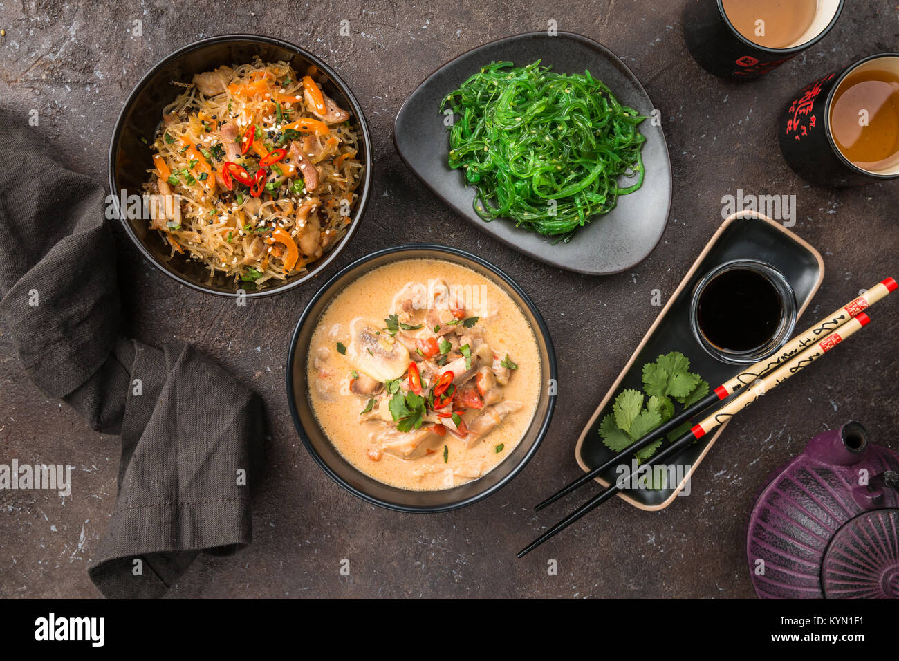 Cibo asiatico, piatti della cucina tailandese. Tom kha gai zuppa, pad thai noodles, insalata verde, salse e tè verde. Vista superiore Foto Stock