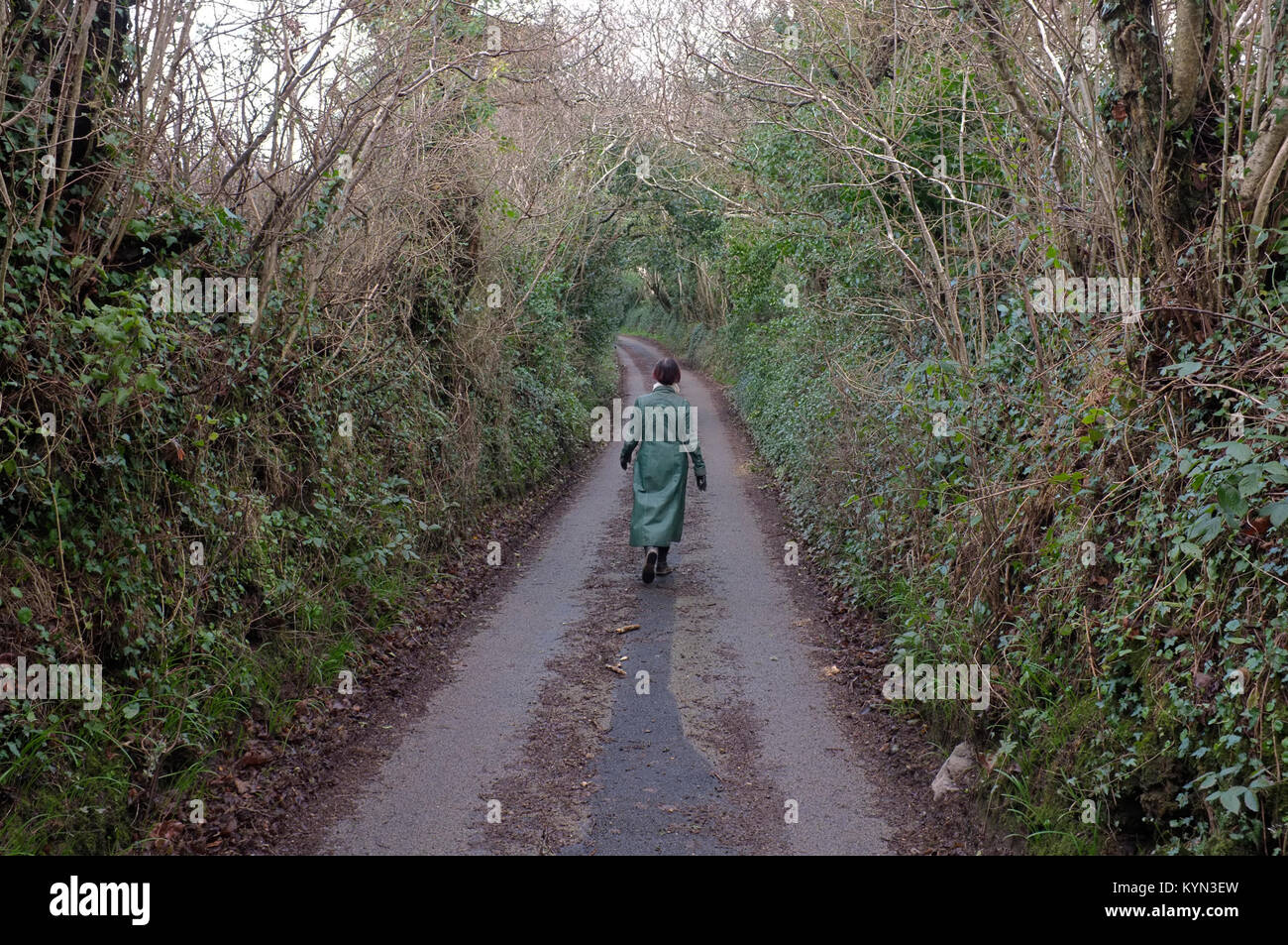 Una donna a piedi lungo una strada di campagna in Cornwall, Regno Unito Foto Stock