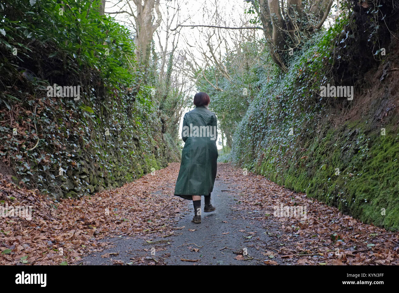 Una donna a piedi lungo una strada di campagna in Cornwall, Regno Unito Foto Stock