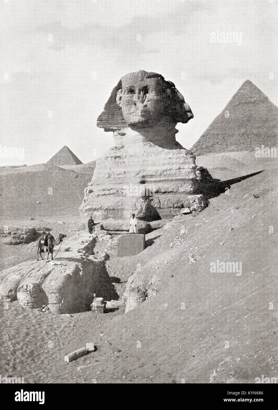 La Grande Sfinge nella Piramide di Giza complesso, altopiano di Giza, Cairo, Egitto. Un imponente scultura generalmente creduto per rappresentare il Faraone Khafre. Visto qui sono lavoratori cancellazione via la sabbia che parzializza la base del monumento. Dalle meraviglie del mondo, pubblicato c.1920. Foto Stock