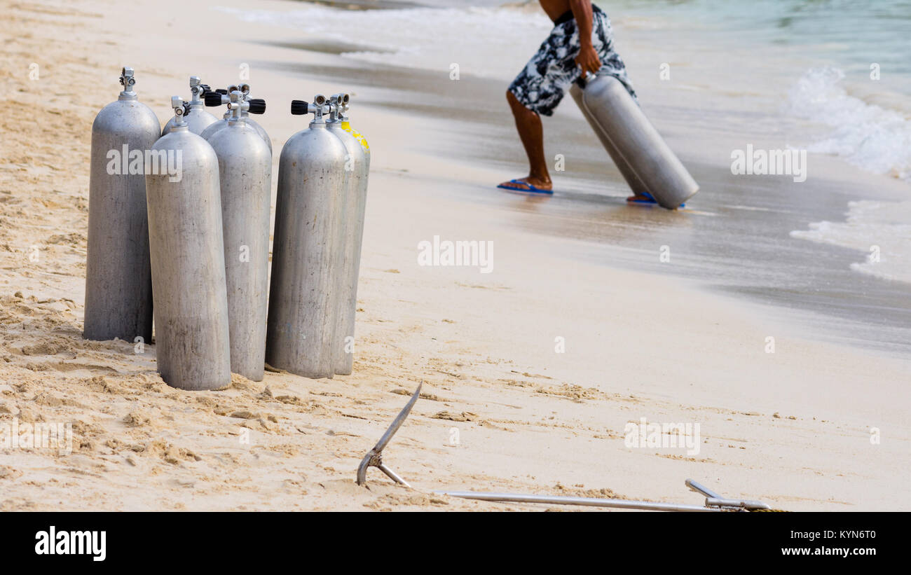 Una collezione di subacquei chiamata richiede aria su un tropicale di spiaggia di sabbia bianca. Foto Stock