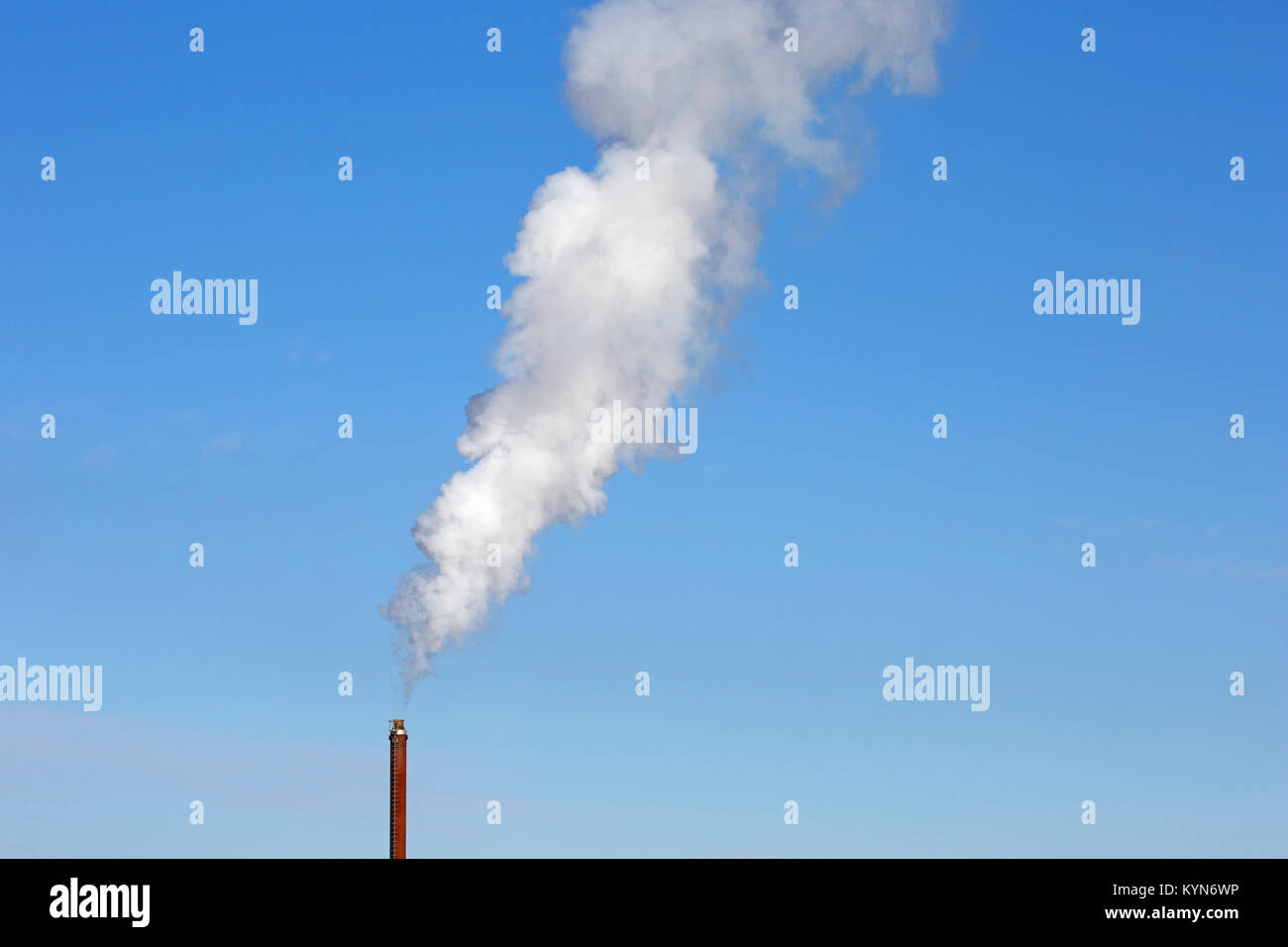 Camino industriale / smoke stack fumaiolo / contro il cielo blu su un giorno windless Foto Stock