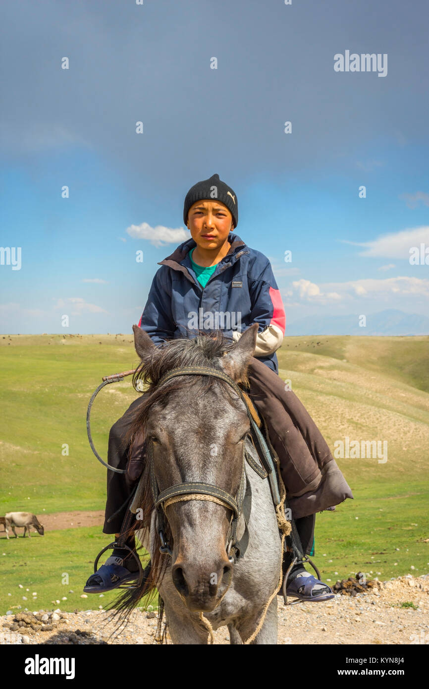 KAZARMAN, Kirghizistan - agosto 14: Locale ragazzo indossa un cappello seduto su un cavallo in remoto del Kirghizistan. Agosto 2016 Foto Stock
