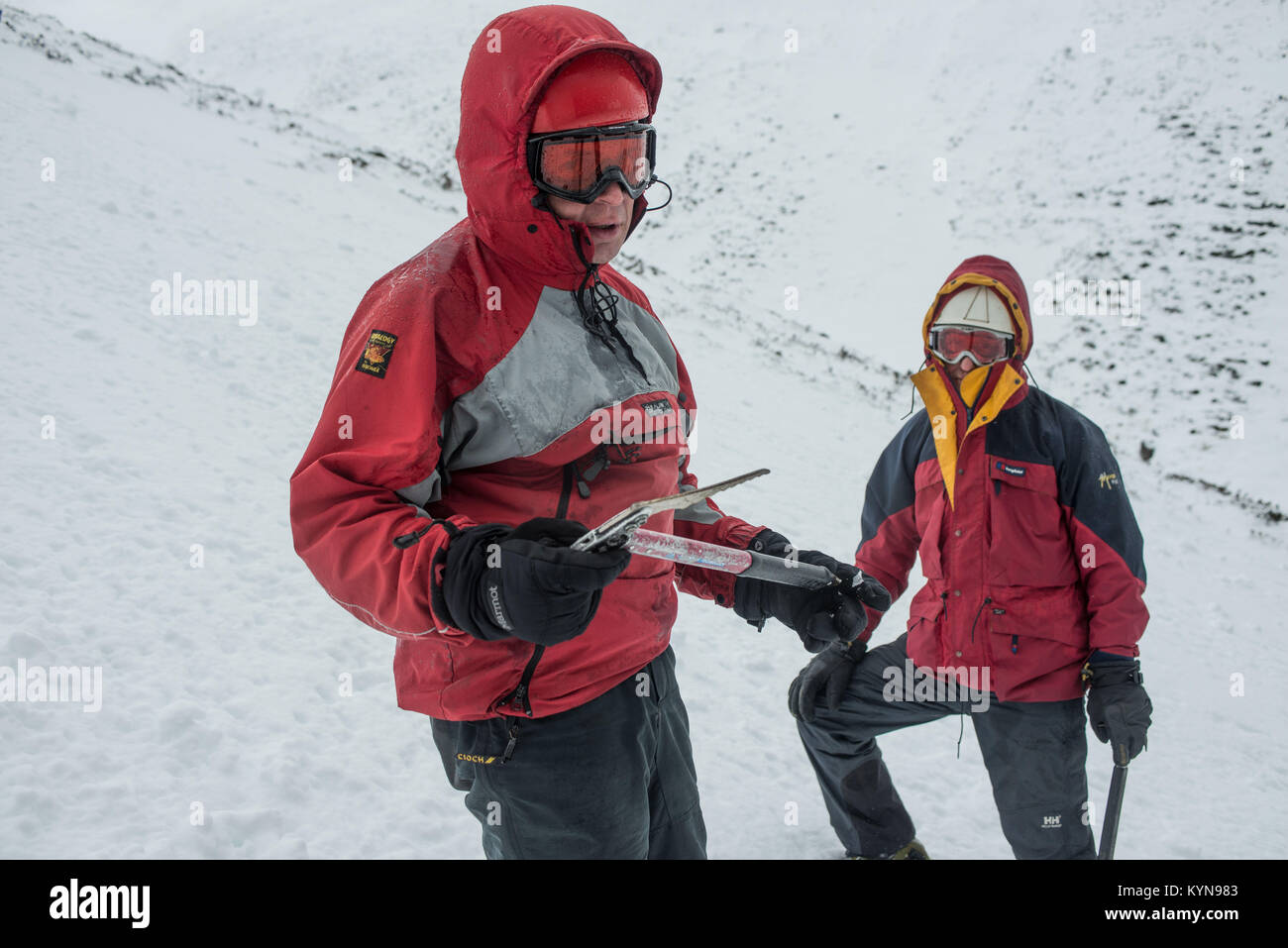 In inverno la formazione di competenze in Cairngorm montagne prima neve viaggio di foratura. Andy dimostrando l'uso di una piccozza - con Wayne dietro. Foto Stock