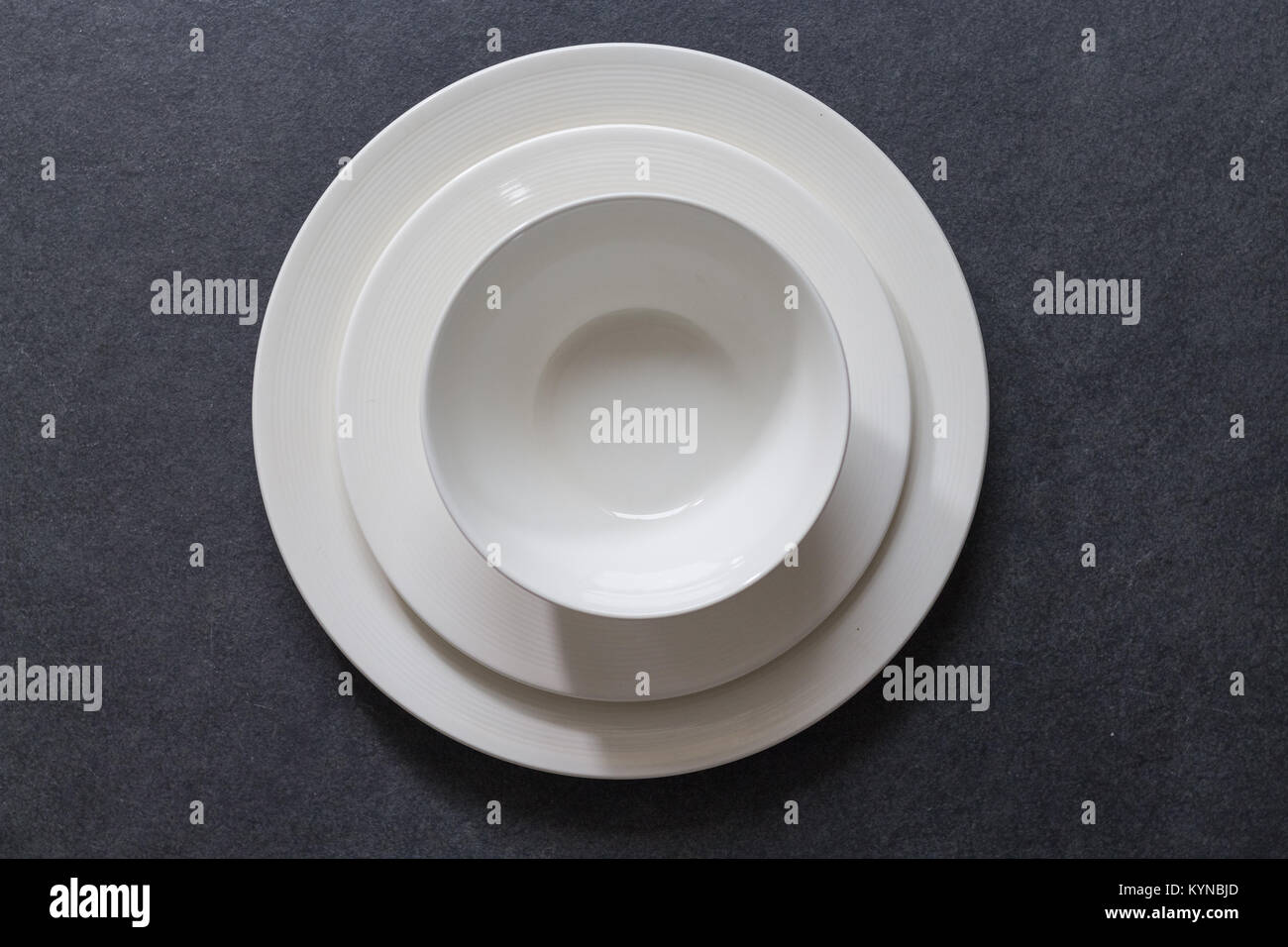 Impostazione tabella con cena piastra rotonda vuoto piastra bianca su sfondo scuro con posate Foto Stock
