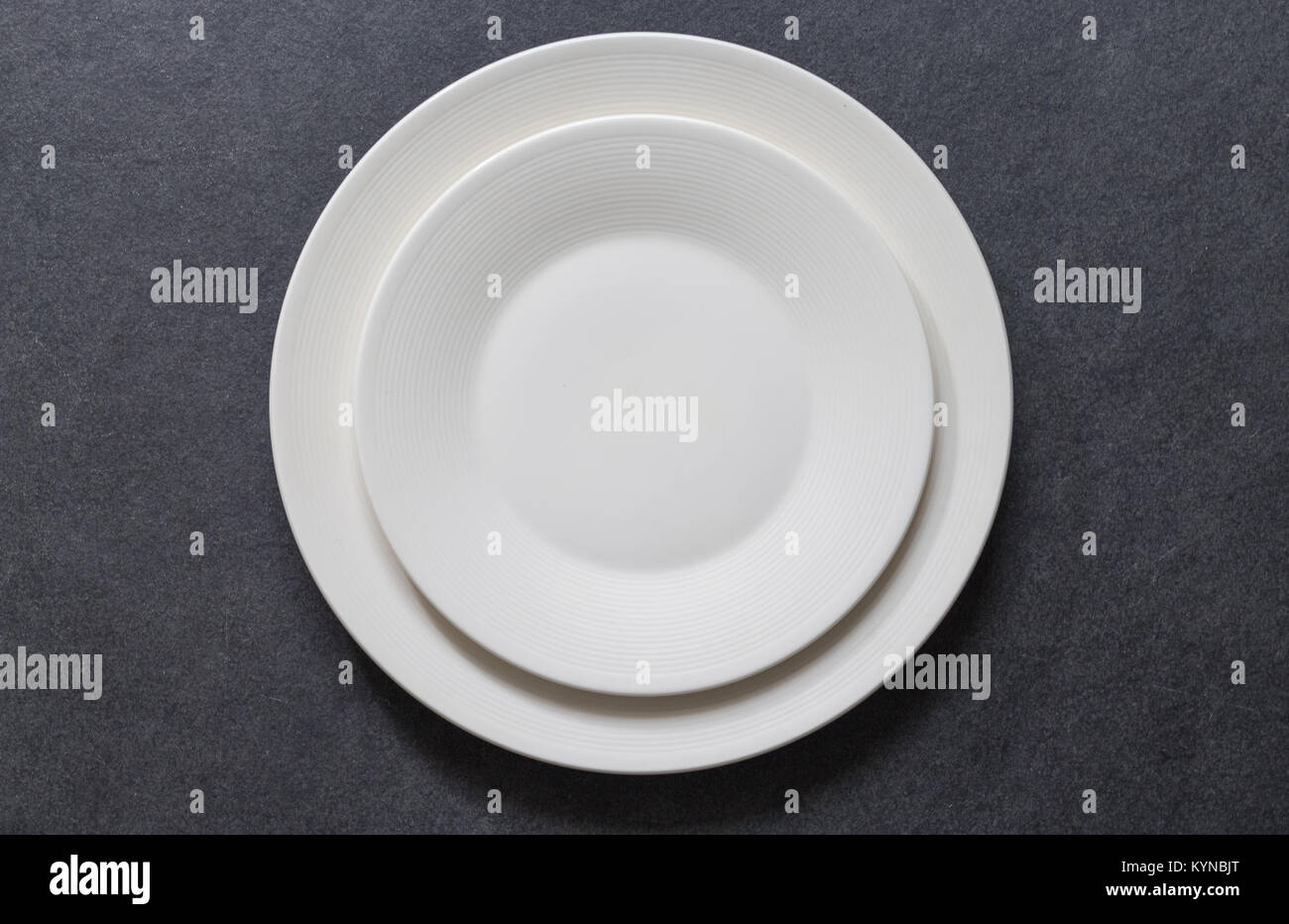 Impostazione tabella con cena piastra rotonda vuoto piastra bianca su sfondo scuro con posate Foto Stock