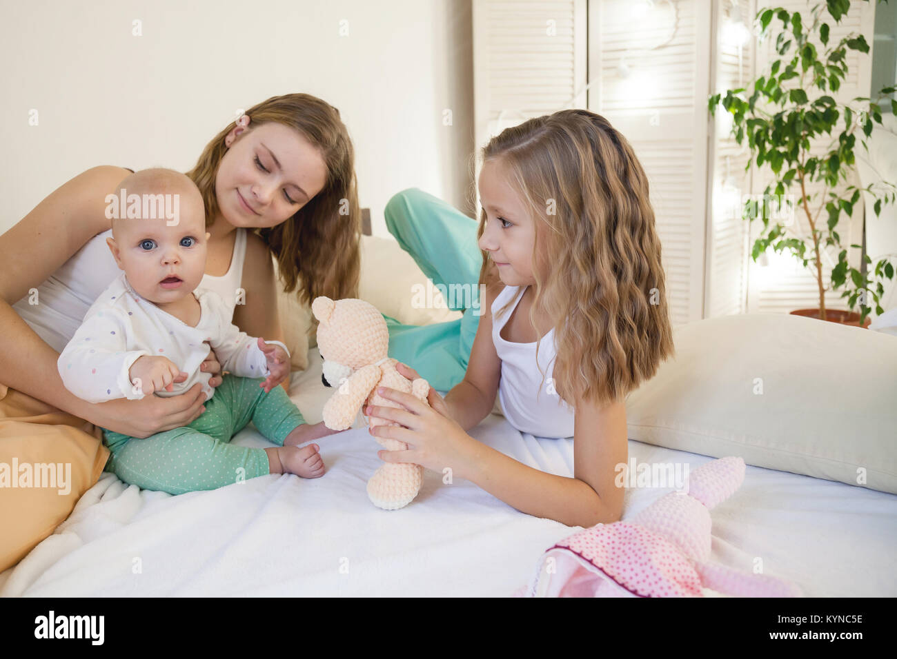 Le tre sorelle Baby girl i bambini al mattino sul letto in camera da letto Foto Stock