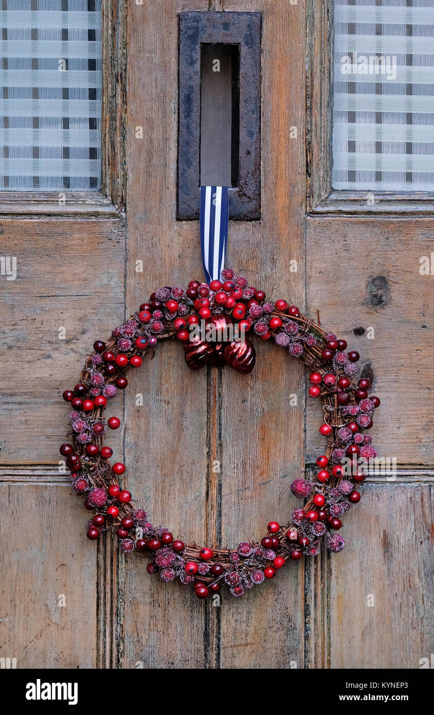 corona di natale di bacche rosse appesa sulla vecchia porta di legno, norfolk, inghilterra Foto Stock