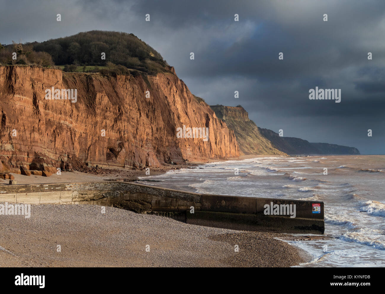 Lo sgretolamento di arenaria rossa e scogliere a Sidmouth, qualora gravi roccia cade ogni anno si verificano,sotto cieli bui Foto Stock