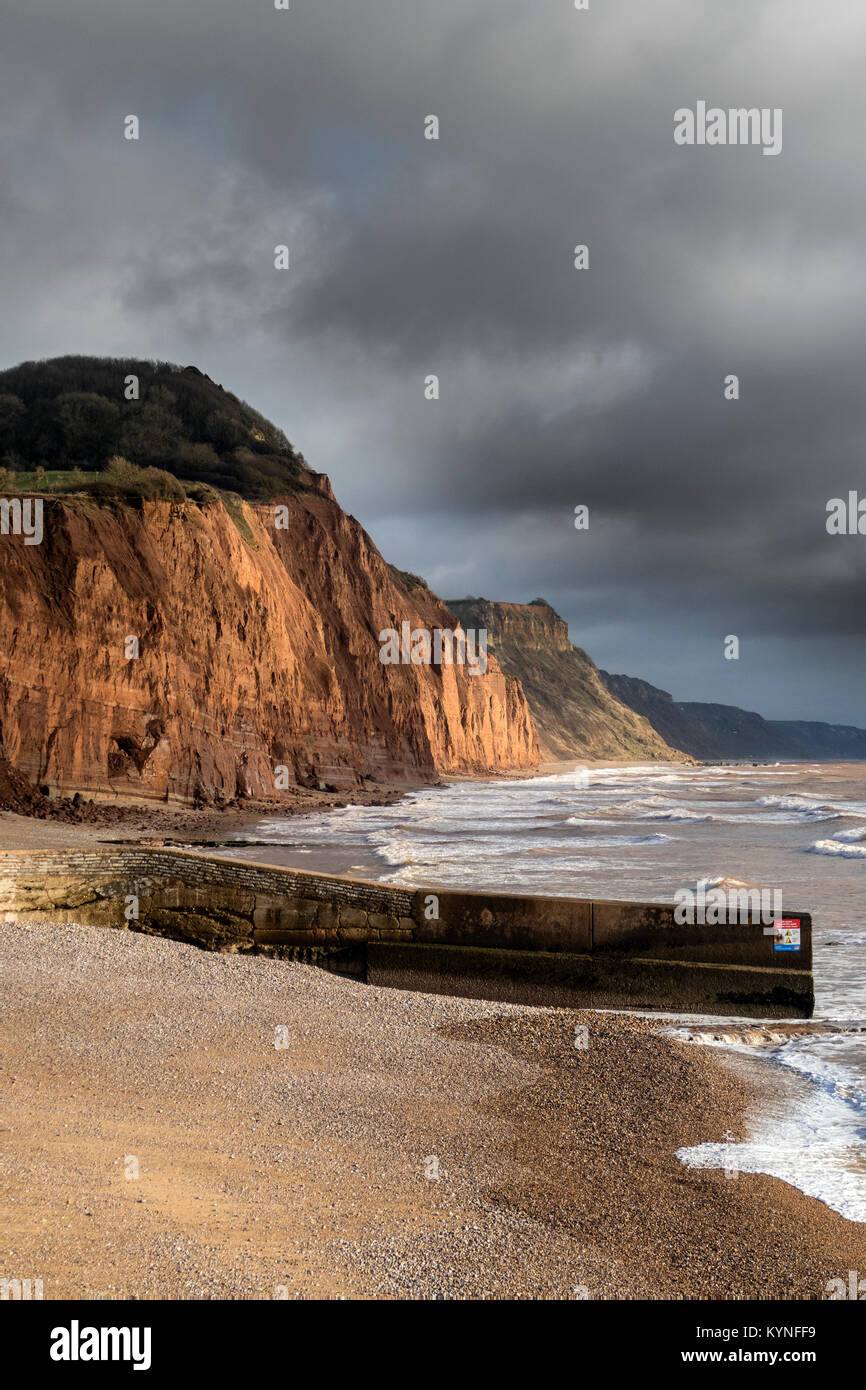 Lo sgretolamento di arenaria rossa e scogliere a Sidmouth, qualora gravi roccia cade ogni anno si verificano,sotto cieli bui Foto Stock