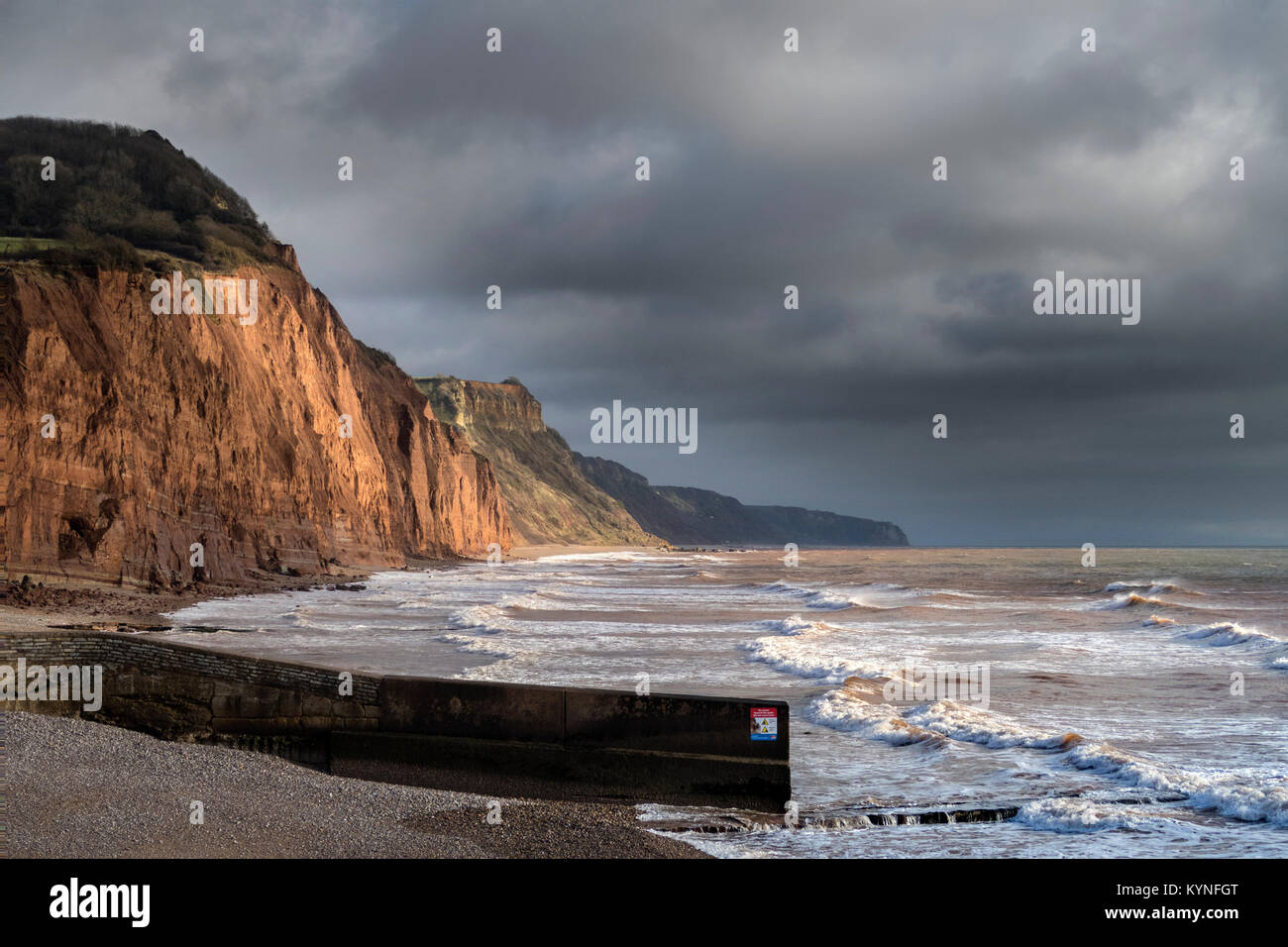 Lo sgretolamento di arenaria rossa e scogliere a Sidmouth, qualora gravi roccia cade ogni anno si verificano,sotto cieli bui Foto Stock